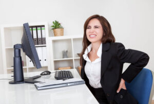 Woman suffers back pain while in the office.